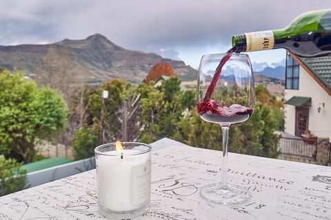 A glass of wine poured on the patio with the mountains behind