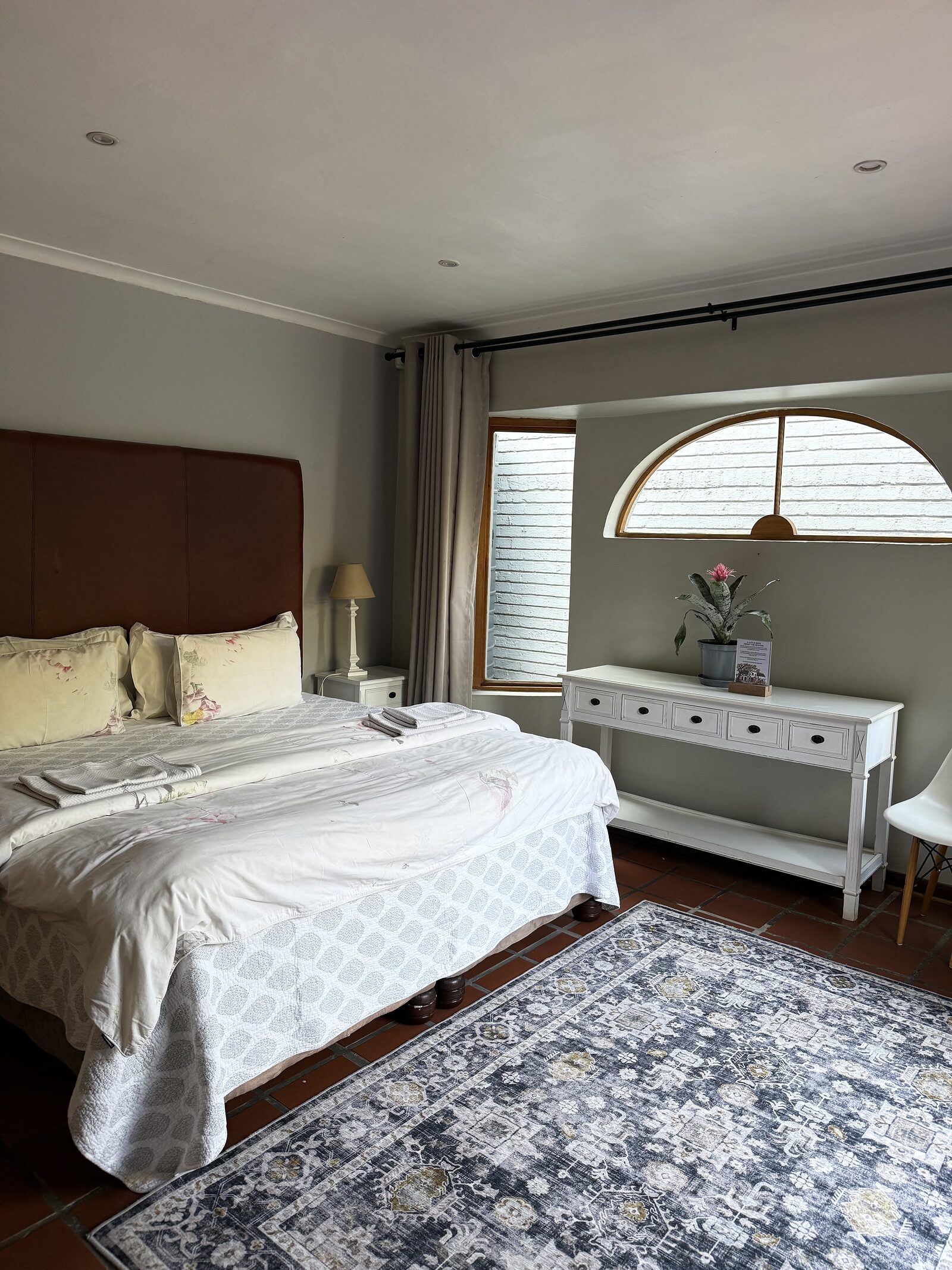The Studio bedroom with its king bed, arched window and patterned rug